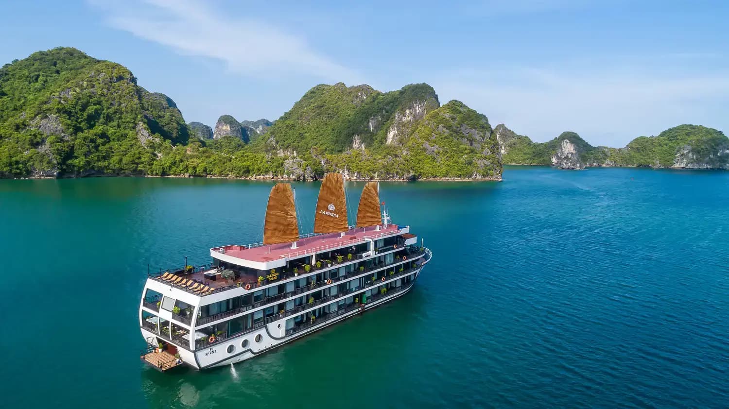 La Regina Grand with red sails in the blue water of Lan Ha Bay