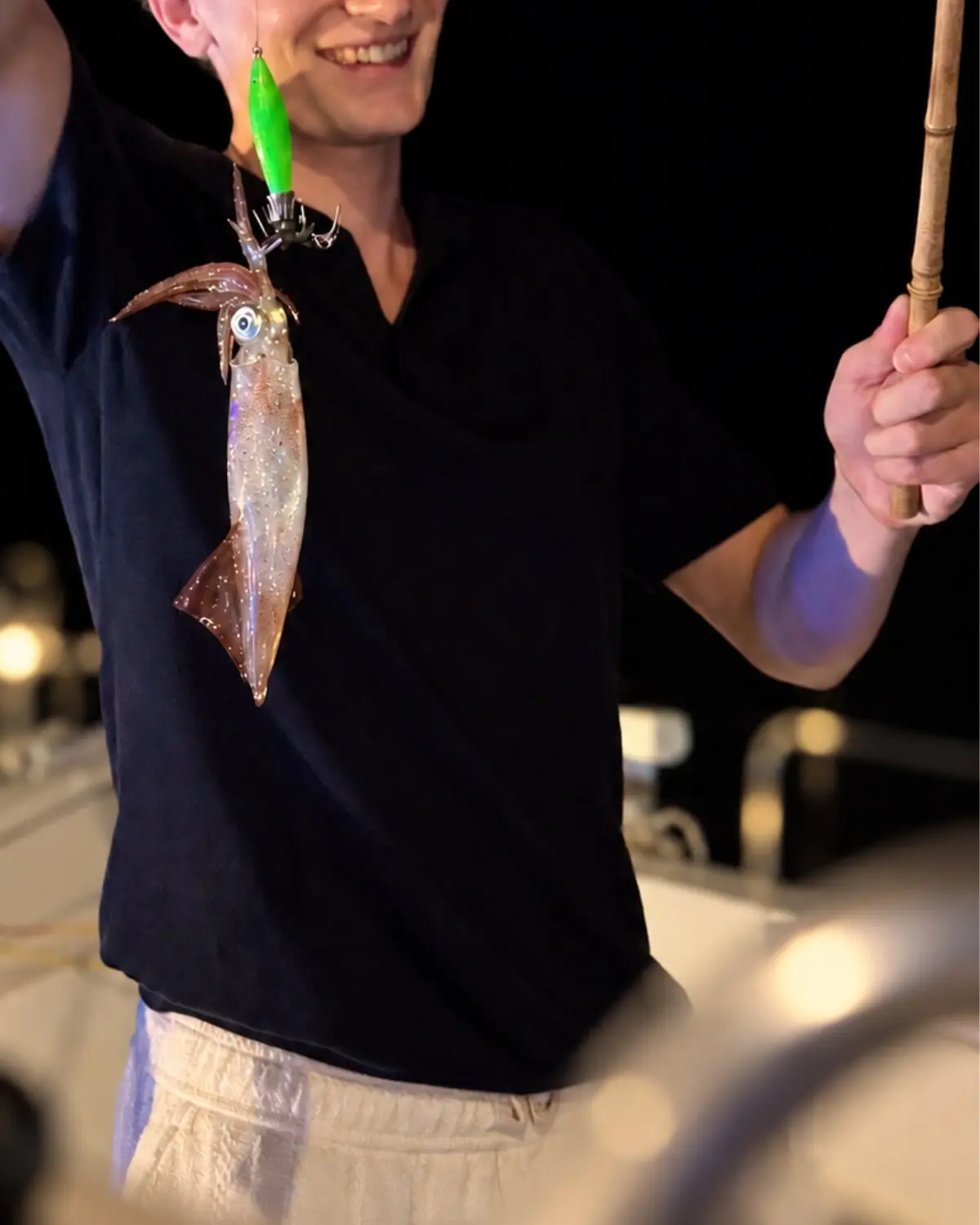 A guest holding up a squid caught at night