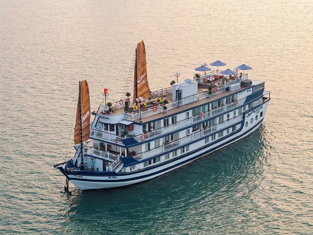 Signature Cruise with its orange sails at sunset in Bai Tu Long Bay