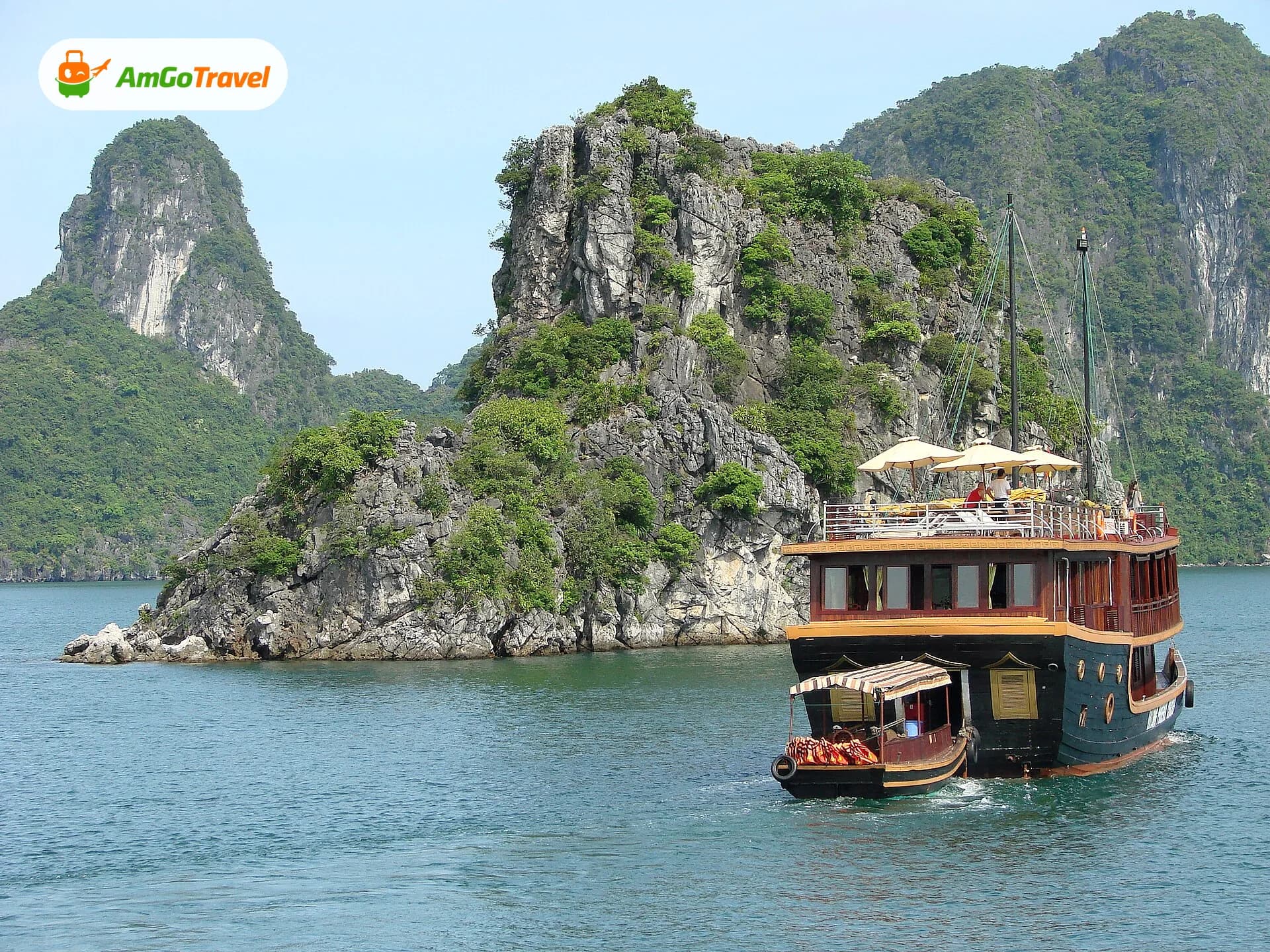 Wooden cruise ship sailing past a limestone islet in Ha Long Bay